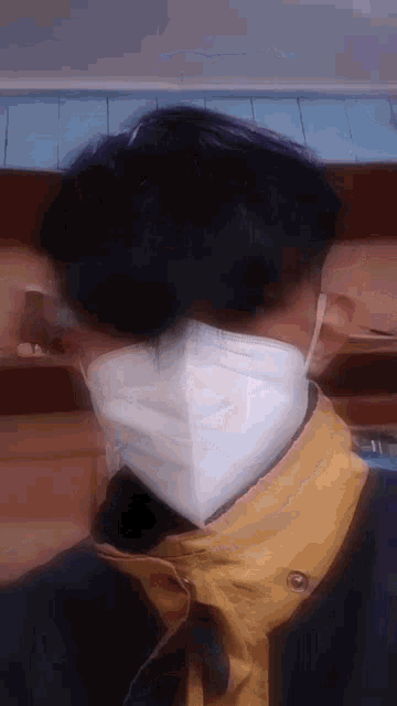 a person wearing a face mask and a yellow jacket .