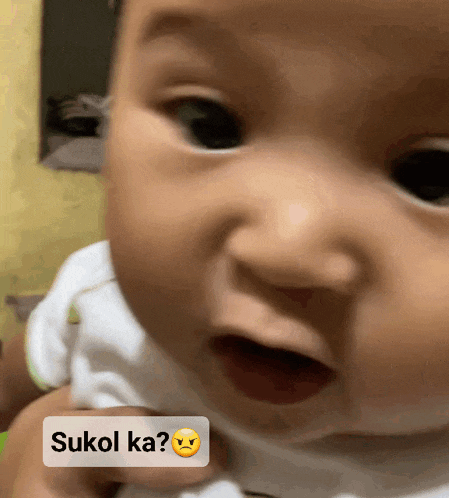 a close up of a baby 's face with a sukol ka sticker