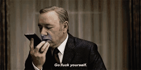 a man in a suit and tie is talking on a cell phone with a purple face painted on his face .