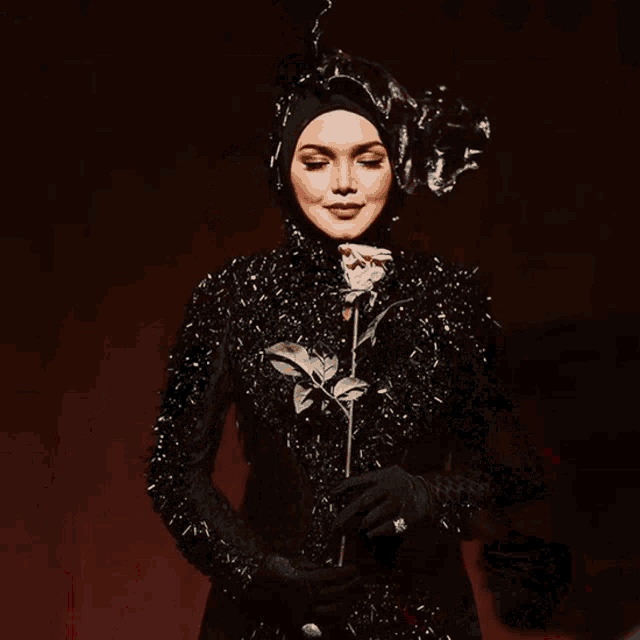 a woman in a black dress holds a rose in her hand