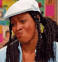 a woman wearing a hat and pigtails is making a funny face .