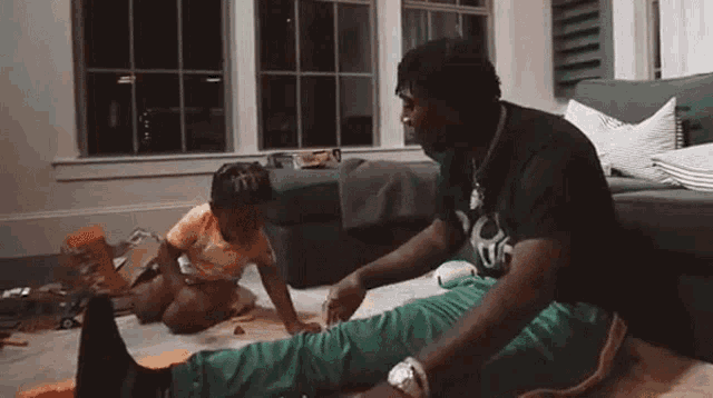 a man and a child are sitting on the floor in a living room playing with toys .