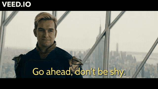 a man is standing in front of a window with the words go ahead don 't be shy