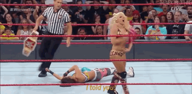 a woman is laying on the ground in a wrestling ring while another woman is standing in the ring .