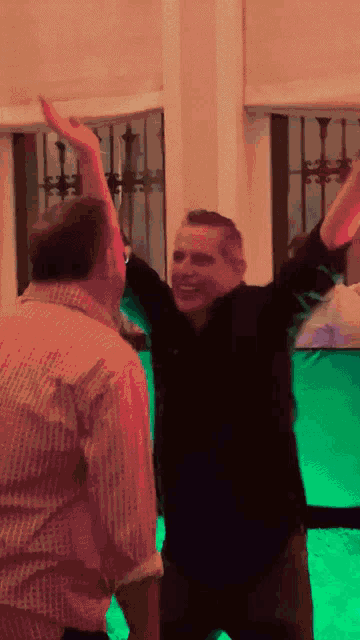 two men are dancing in a room with a green light behind them