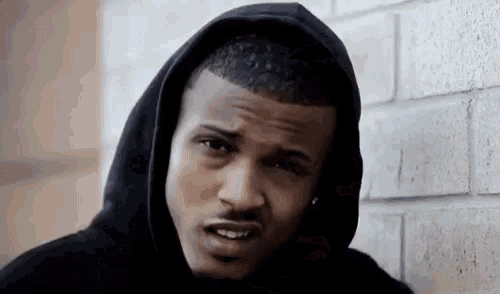 a man wearing a black hoodie looks at the camera