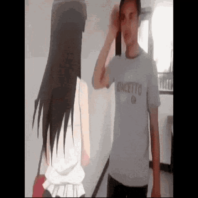 a man wearing a concepto t-shirt is standing next to a woman