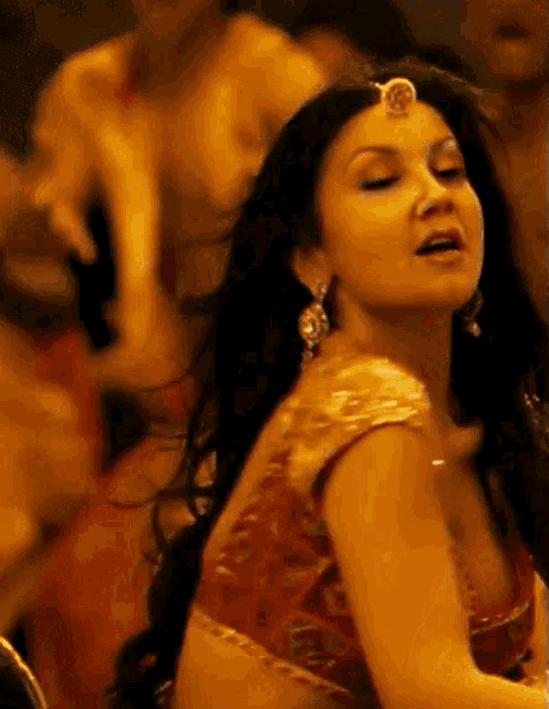 a woman in a red top is dancing with her eyes closed .