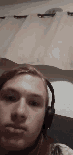 a young man wearing headphones is sitting in front of a curtain