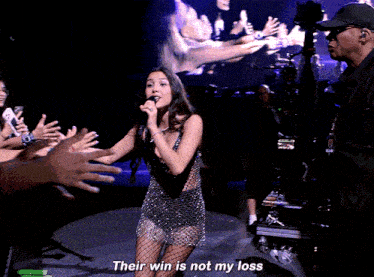 a woman singing into a microphone with the words " their win is not my loss " next to her
