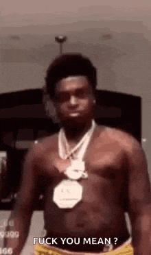 a shirtless man wearing a necklace and shorts is standing in front of a camera .