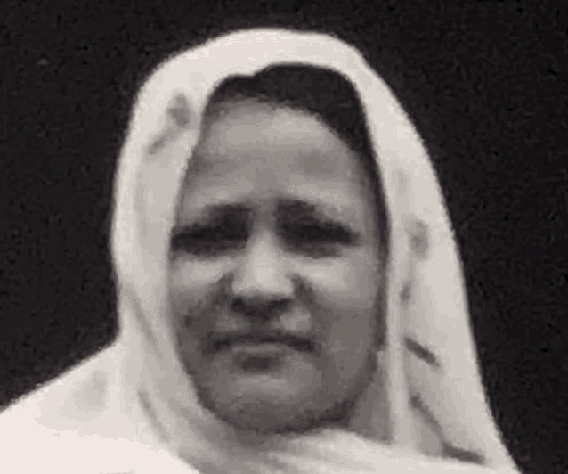 a black and white photo of a woman wearing a white scarf around her head .