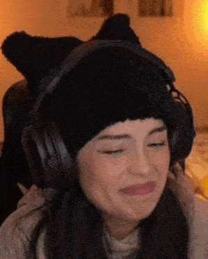 a woman wearing headphones and a black hat is making a funny face .