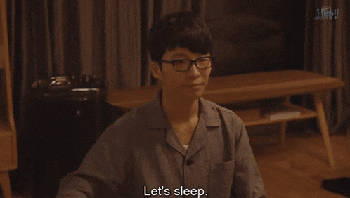 a man wearing glasses and pajamas is holding a remote control and says let 's sleep