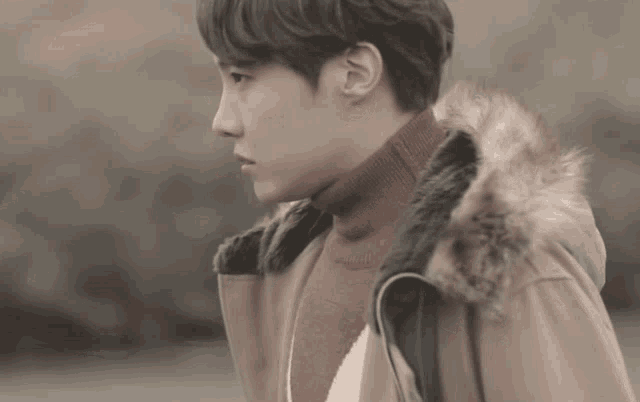 a young man wearing a turtleneck and a fur hooded coat