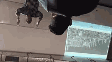 a man is upside down in front of a projection screen