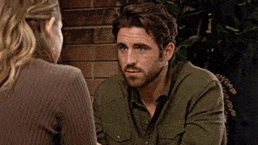 a man in a green shirt talks to a woman