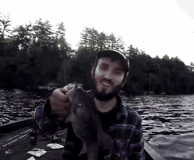 a man in a plaid shirt is holding a large fish