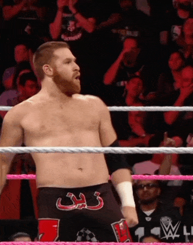 a shirtless wrestler in a ring with a crowd watching