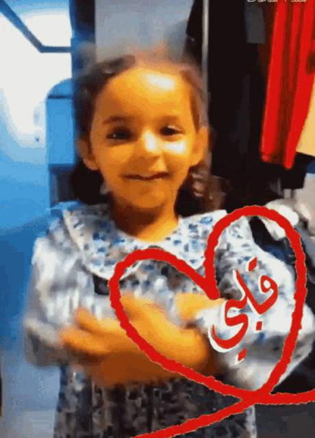 a little girl in a blue and white dress with a red heart with the word flay written on it