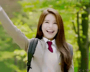 a girl in a school uniform with a backpack is smiling