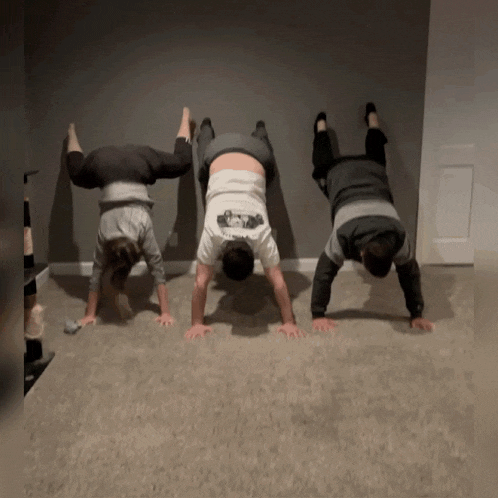 three people doing handstand exercises with one wearing a shirt that says ' i love you ' on the back