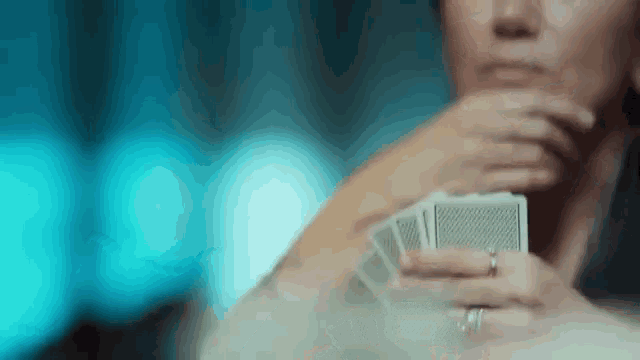a woman with a ring on her finger is holding a stack of playing cards