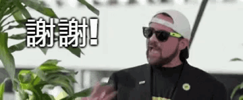 a man wearing sunglasses and a hat is standing in front of a building with chinese writing on it .