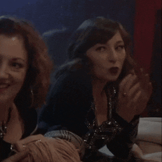 two women are sitting next to each other in a dark room and smiling