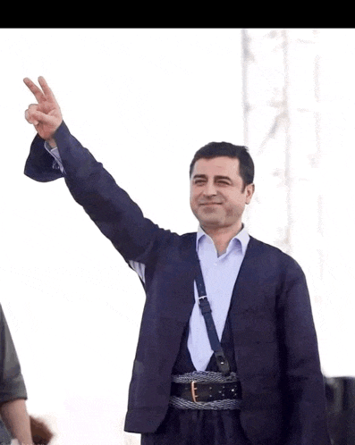 a man in a suit giving a peace sign with his hand