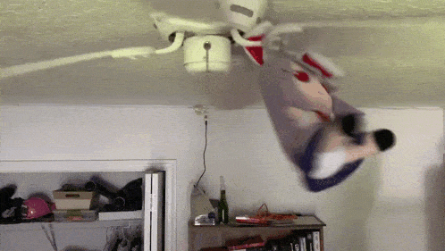 a stuffed animal hanging from a ceiling fan in a living room