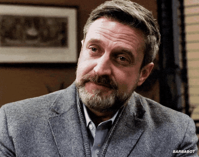 a man with a beard is wearing a grey jacket and a blue shirt with barbabot written on the bottom