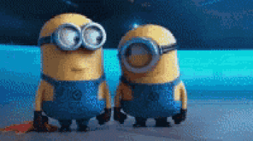 two minions wearing goggles are standing next to each other on the beach .