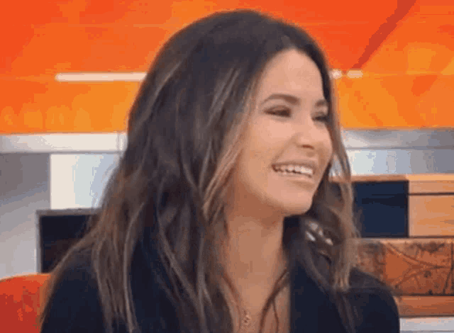 a woman with long dark hair is smiling and looking at the camera