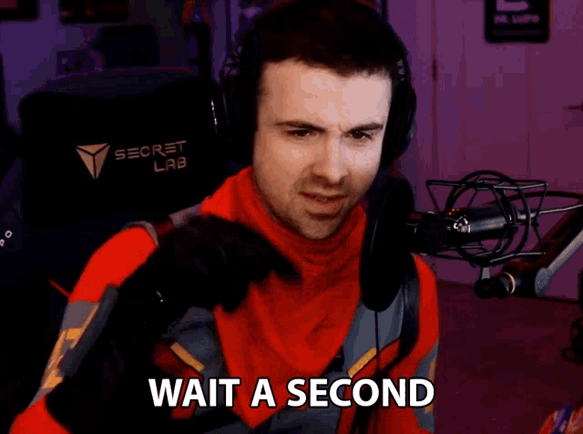 a man wearing headphones and a red outfit says wait a second