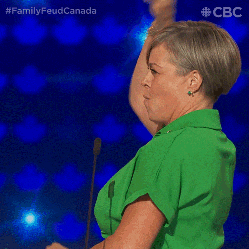 a woman in a green shirt is standing in front of a microphone with her arm in the air ..