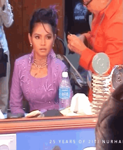 a woman in a purple dress sits in front of a mirror