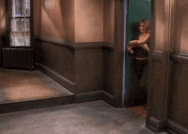 a woman is standing in a hallway with a book in her hand