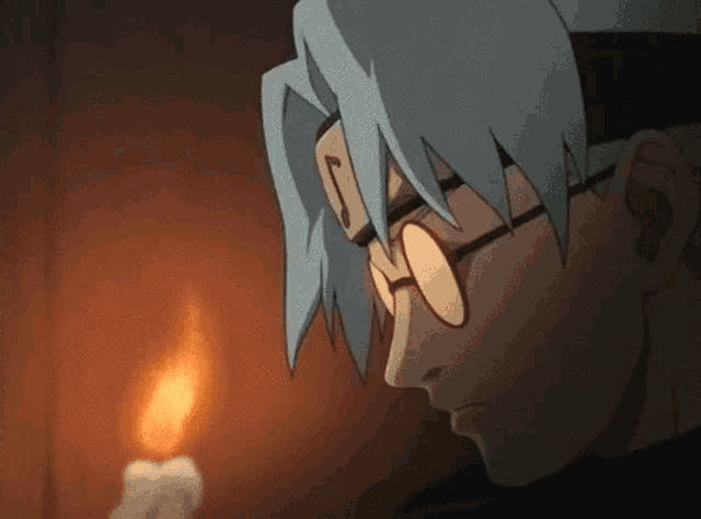 a man wearing glasses is looking at a candle .