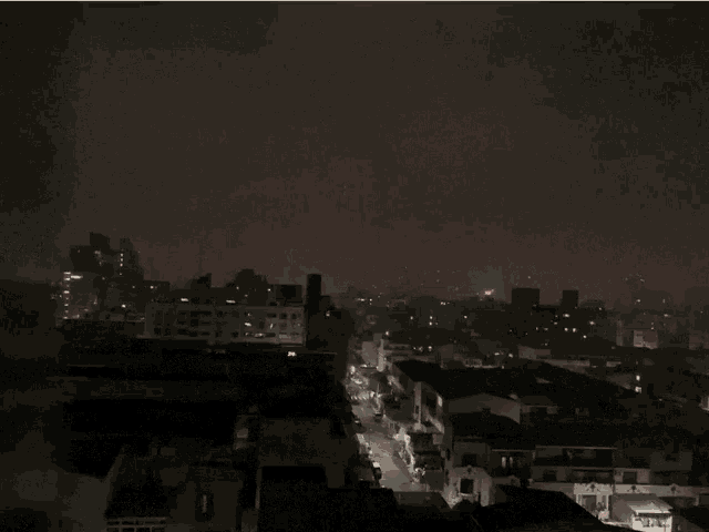 an aerial view of a city at night with a bright light coming out of the sky