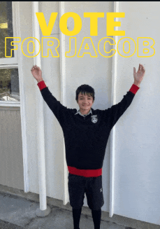 a boy with his arms in the air is standing in front of a wall that says vote for jacob
