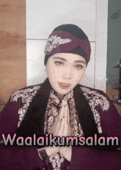 a woman wearing a turban and a purple jacket is saying waalaikumsalam