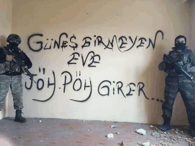 two soldiers are standing in front of a wall that has graffiti on it