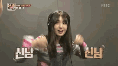 a woman wearing headphones is dancing in front of a sign that says kbs2 on it .