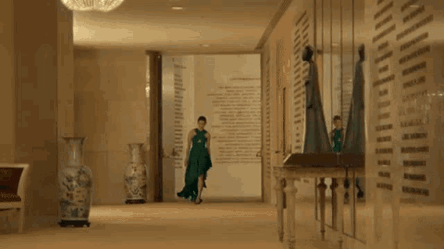 a woman in a green dress is dancing in a hallway with vases
