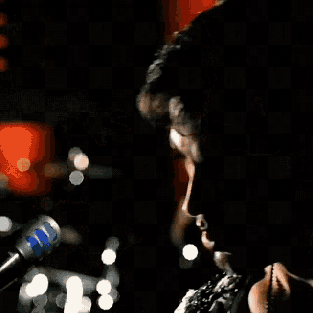 a man is singing into a microphone with a blue stripe on it