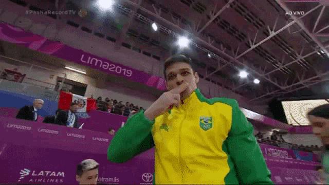 a man in a yellow and green jacket stands in front of a banner that says lima 2019