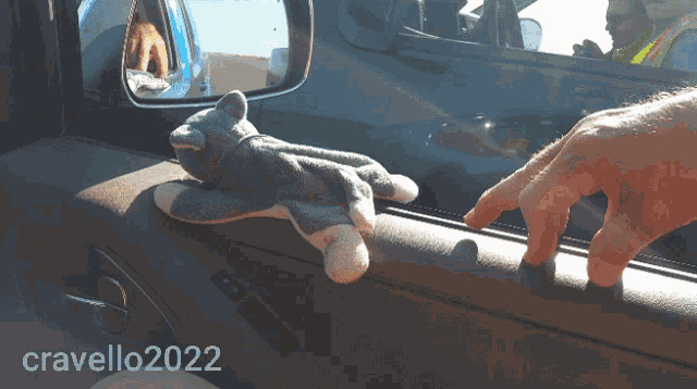 a person holding a stuffed animal in a car door with the year 2022 on the bottom right