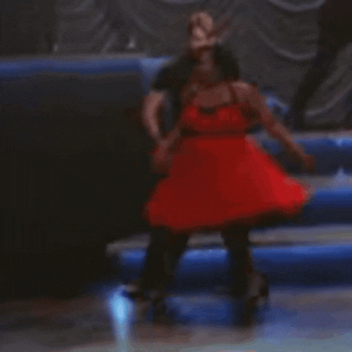a woman in a red dress is dancing on a stage with a man