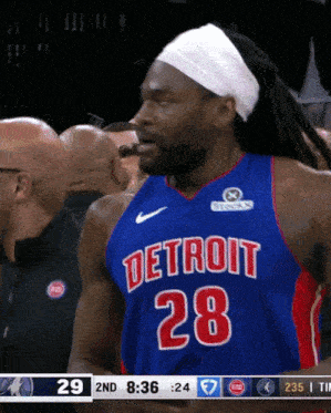 a basketball player wearing a detroit 28 jersey is eating something